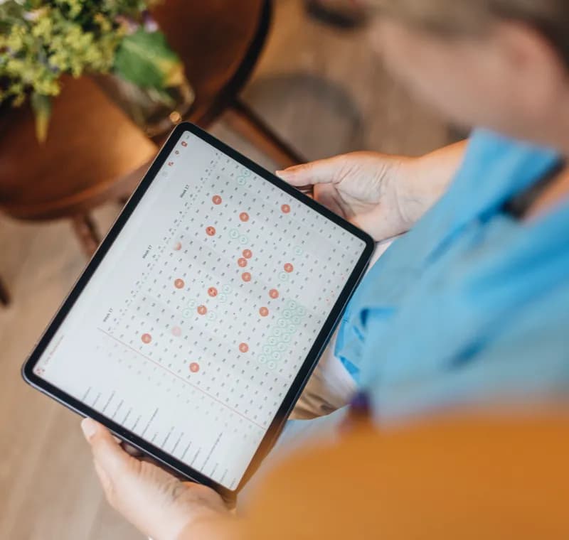 A home caregiver holds technology that shows an integrated structured planning
