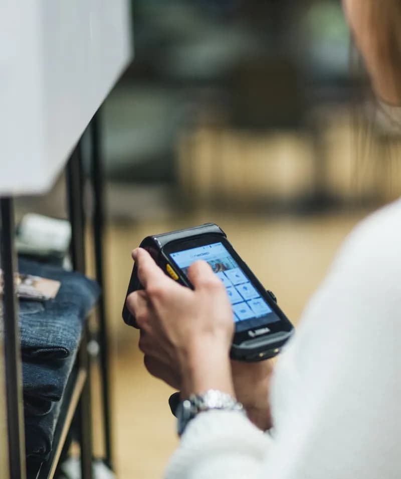 A retail worker from a clothing store holds technology that helps her count her inventory in real-time
